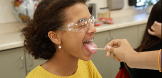 a student wrinkles her nose and closes her eyes tight as she taste tests a solution from a cotton swab