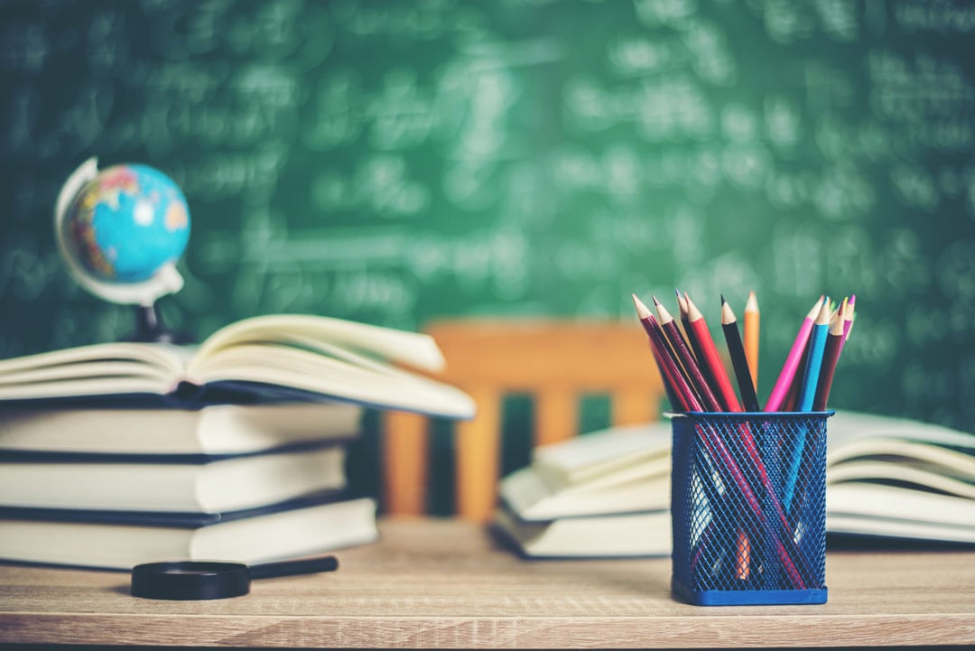 A-jar-of-pencils-with-books,-globe,-and-magnifying-glass-in-background