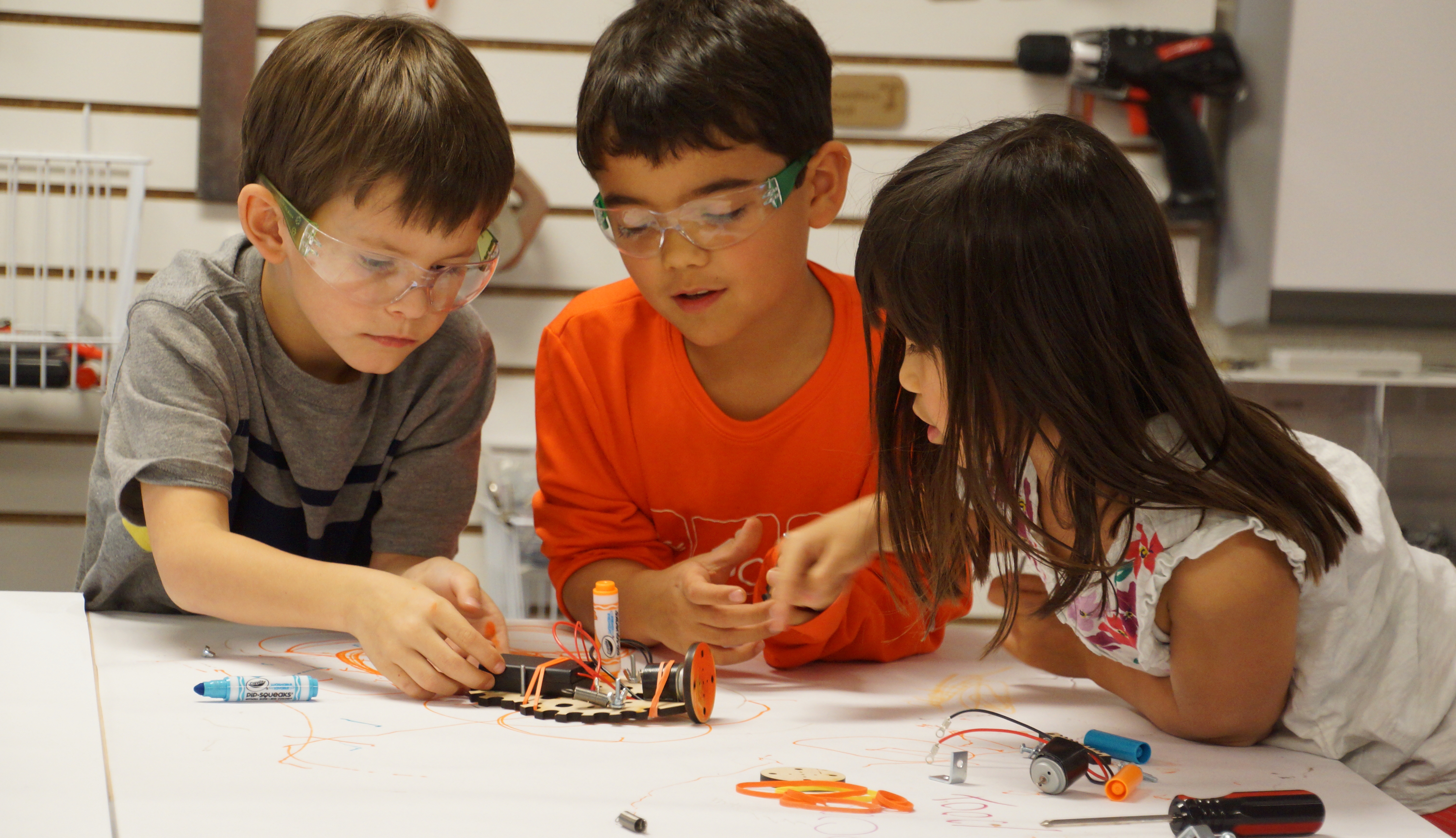 three students collaborate on a tinkering challenge