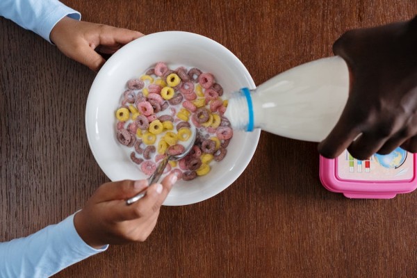 Milk being poured over a bowl of cereal